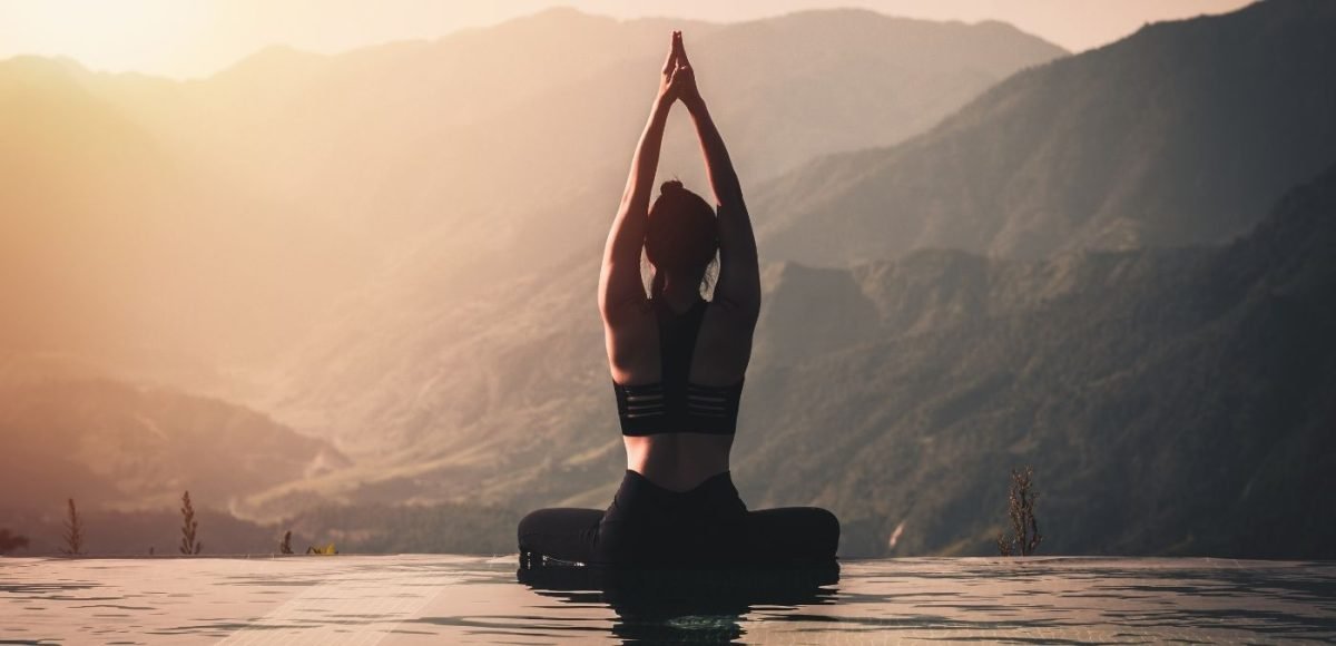 a woman does yoga on an infinity pool edge