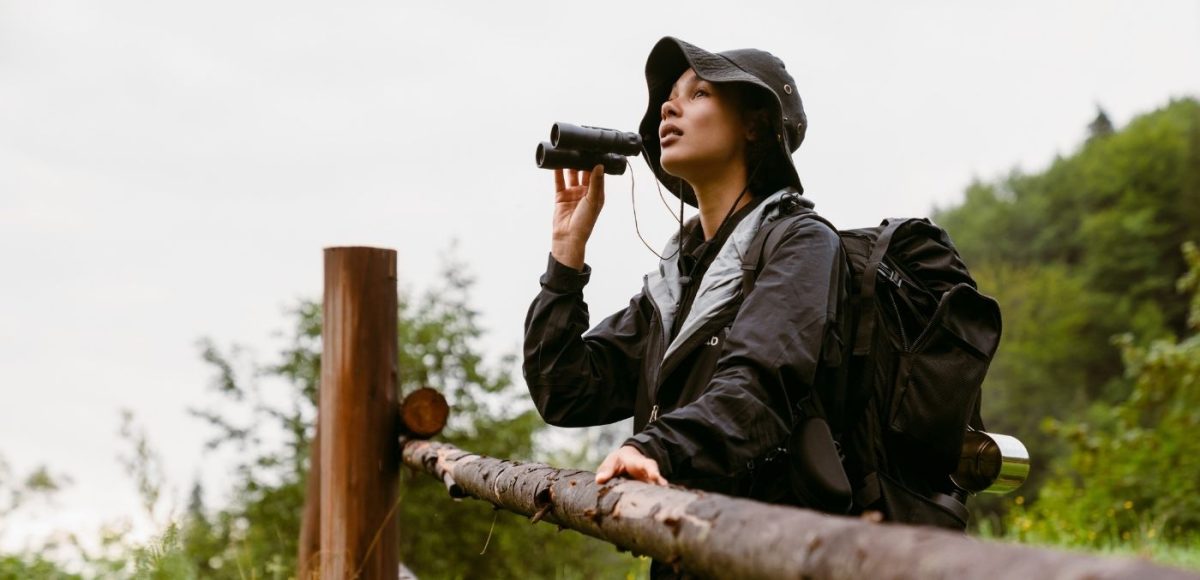 woman standing at fence with binoculars