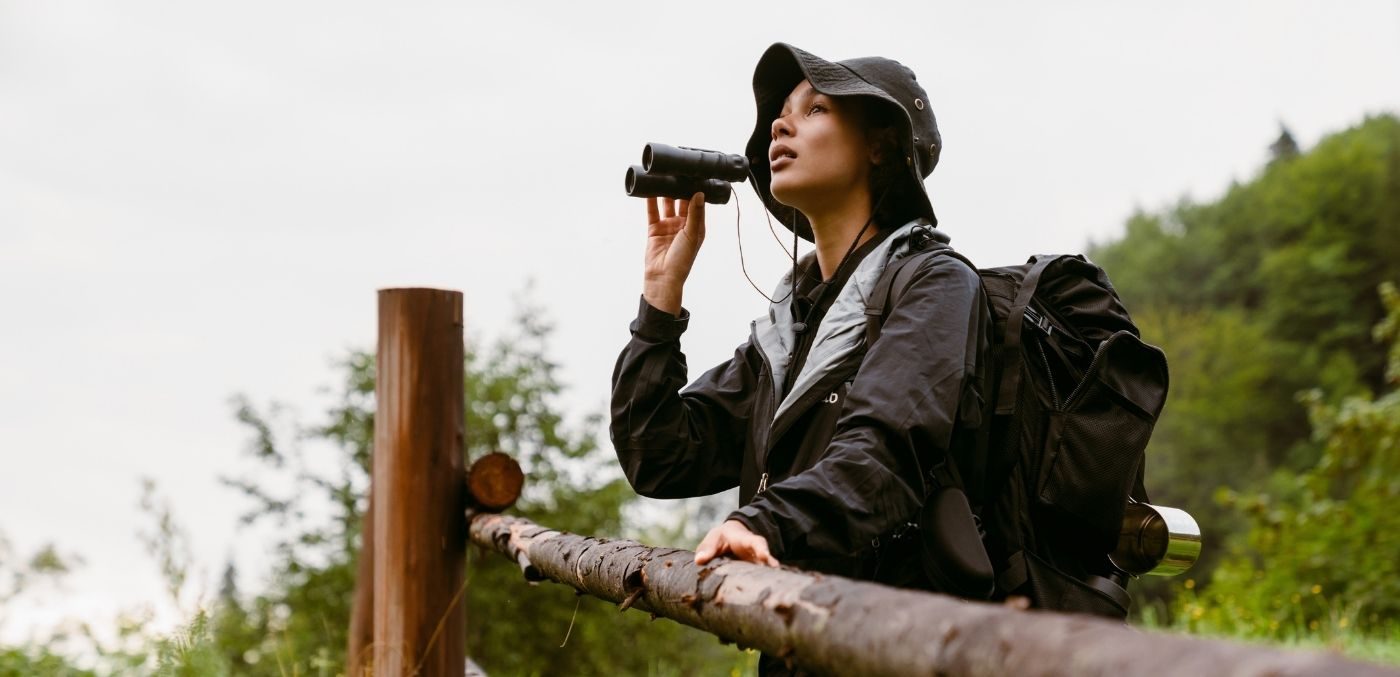 woman standing at fence with binoculars