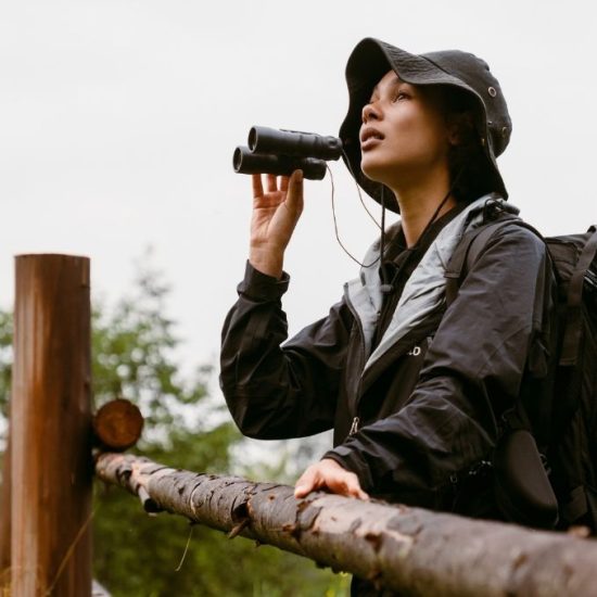 woman standing at fence with binoculars