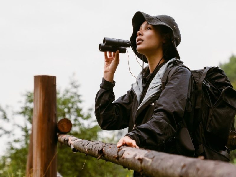 woman standing at fence with binoculars